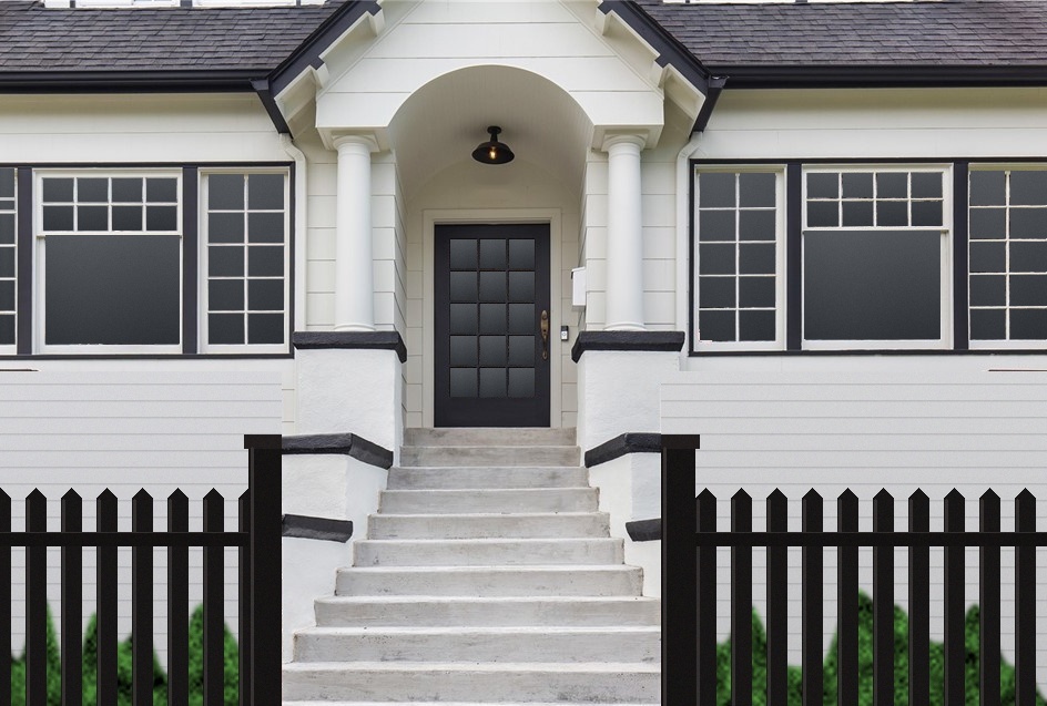 A white Craftsman-style home with black-trimmed windows, an arched entry porch with columns, and wide stairs leading to a black glass-paned front door