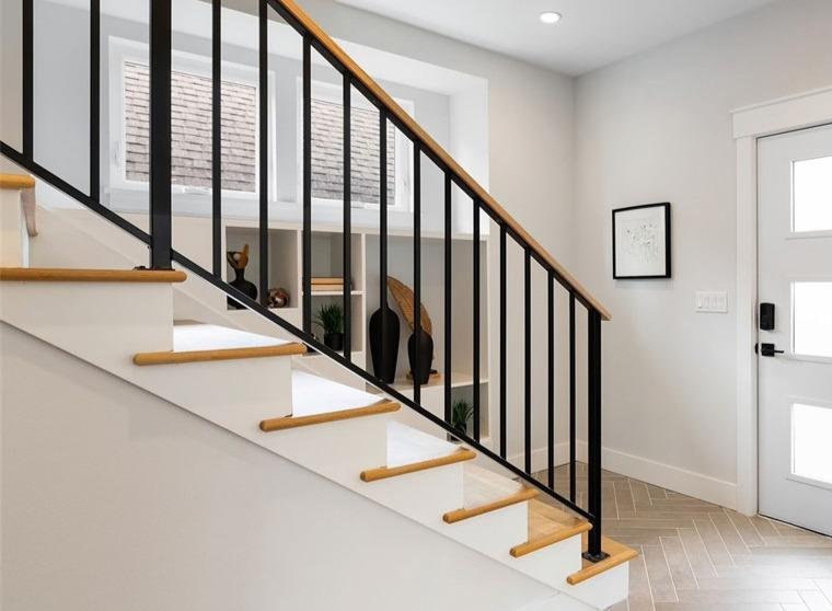 A light-filled entry with a white staircase, oak treads, and a slim black steel railing